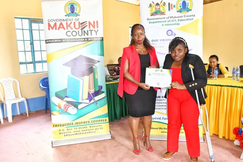 A participant receiving a certificate at the closing event for Makueni’s seventh internship cohort.
